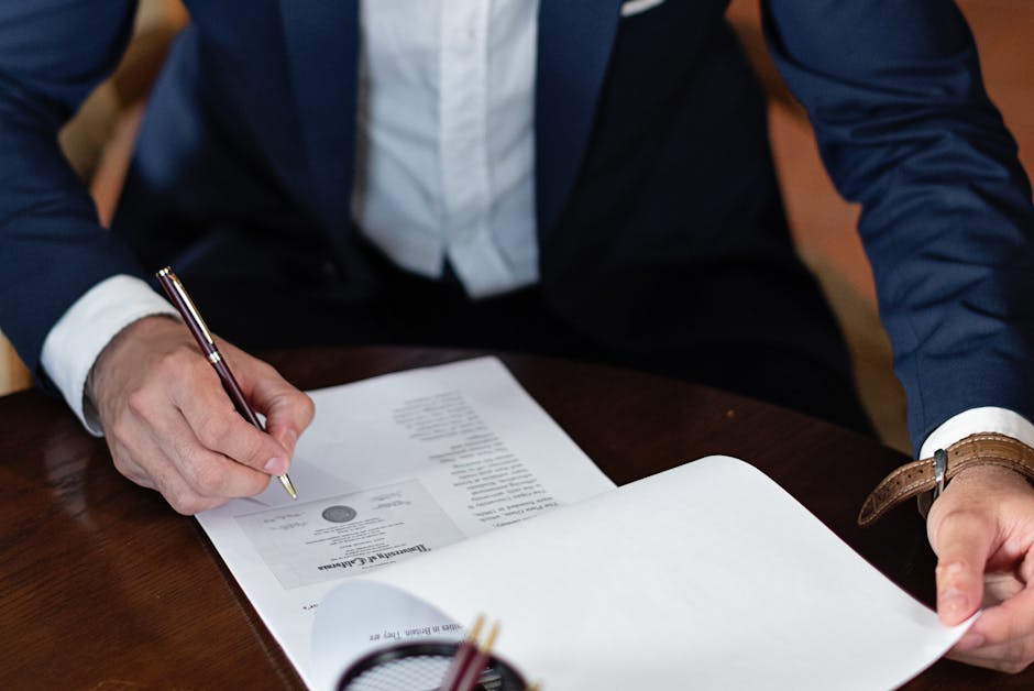 A professional individual signs legal documents at a desk in an office setting